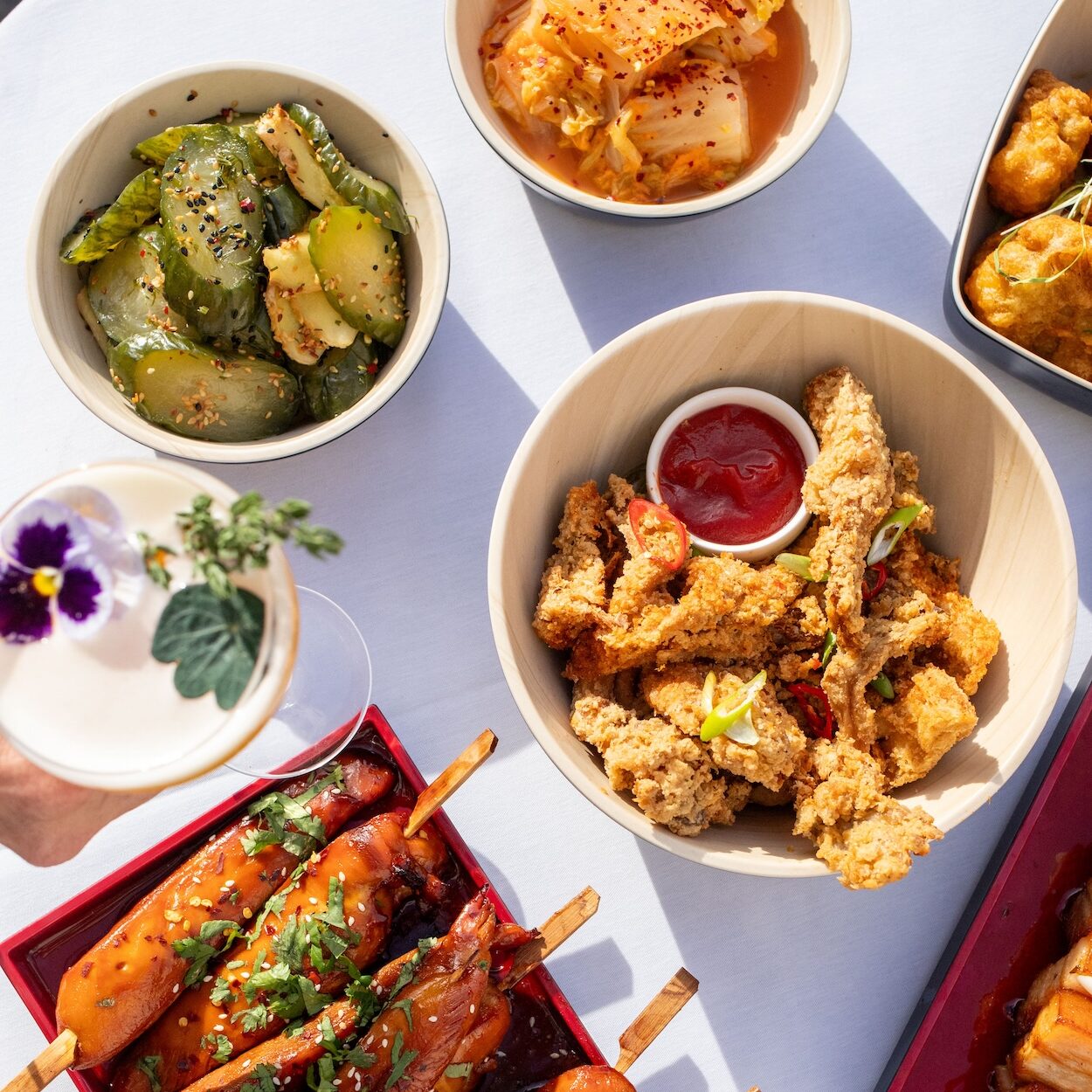 Colourful table spread at The Square Club in Bristol featuring Korean BBQ dishes, kimchi, fried chicken and cocktails. A top summer party venue for private and corporate celebrations.